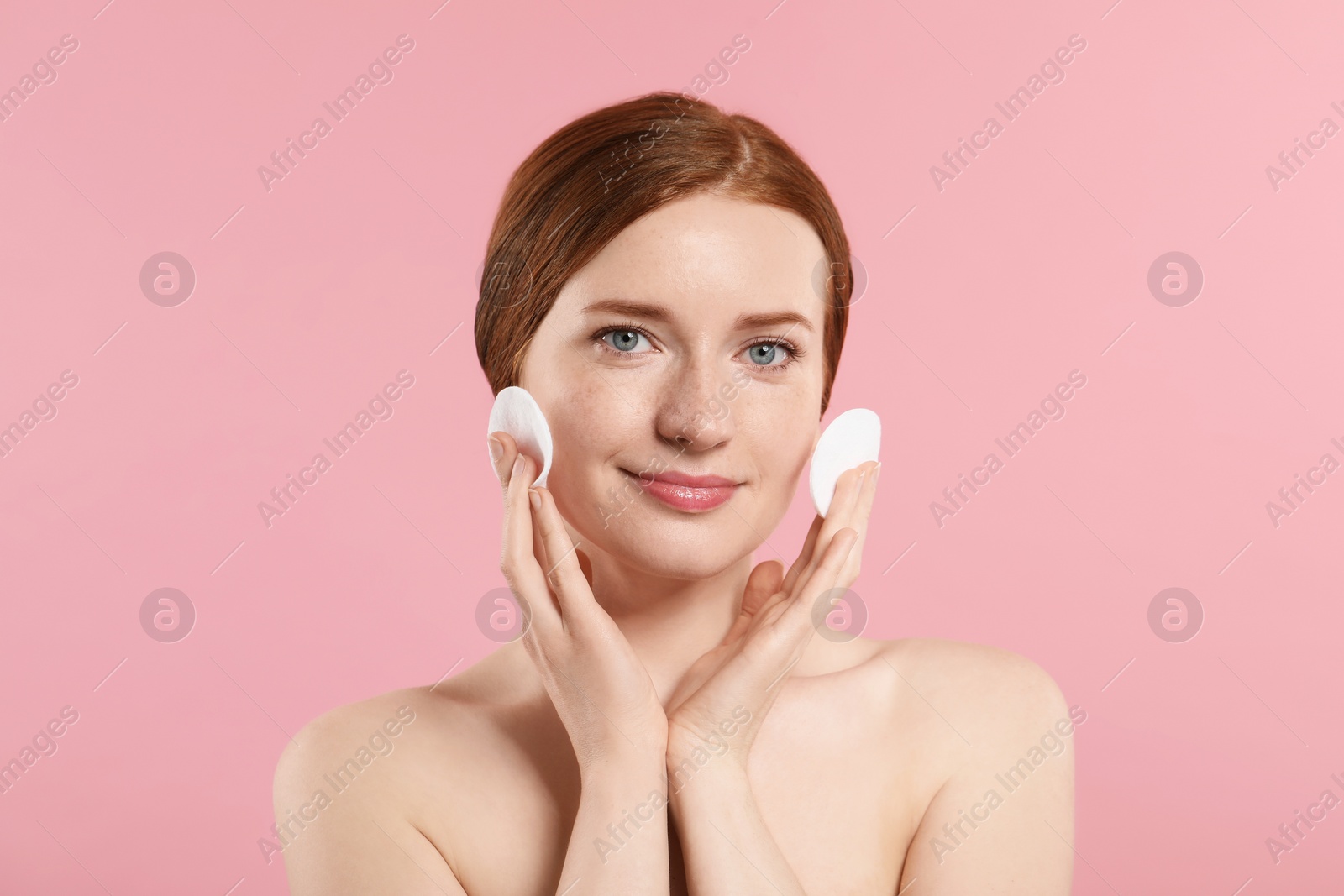 Photo of Beautiful woman with freckles wiping face on pink background