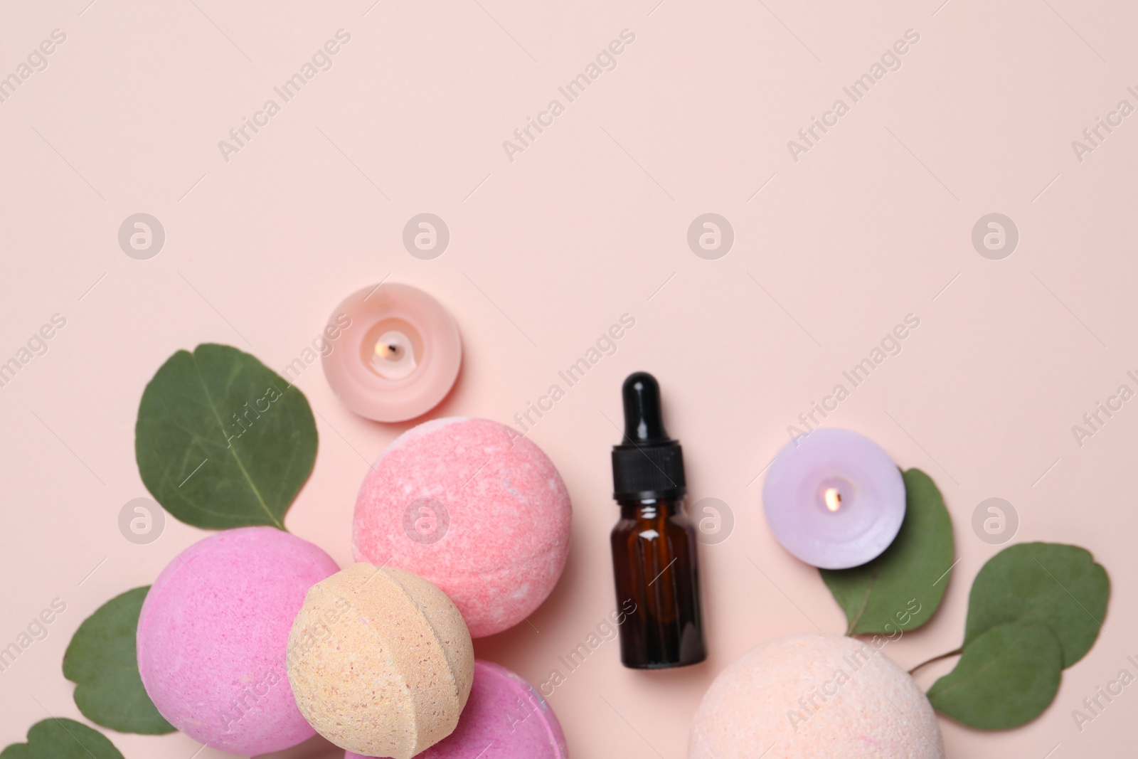 Photo of Bath bombs, eucalyptus leaves, burning candles and bottle on beige background, flat lay. Space for text