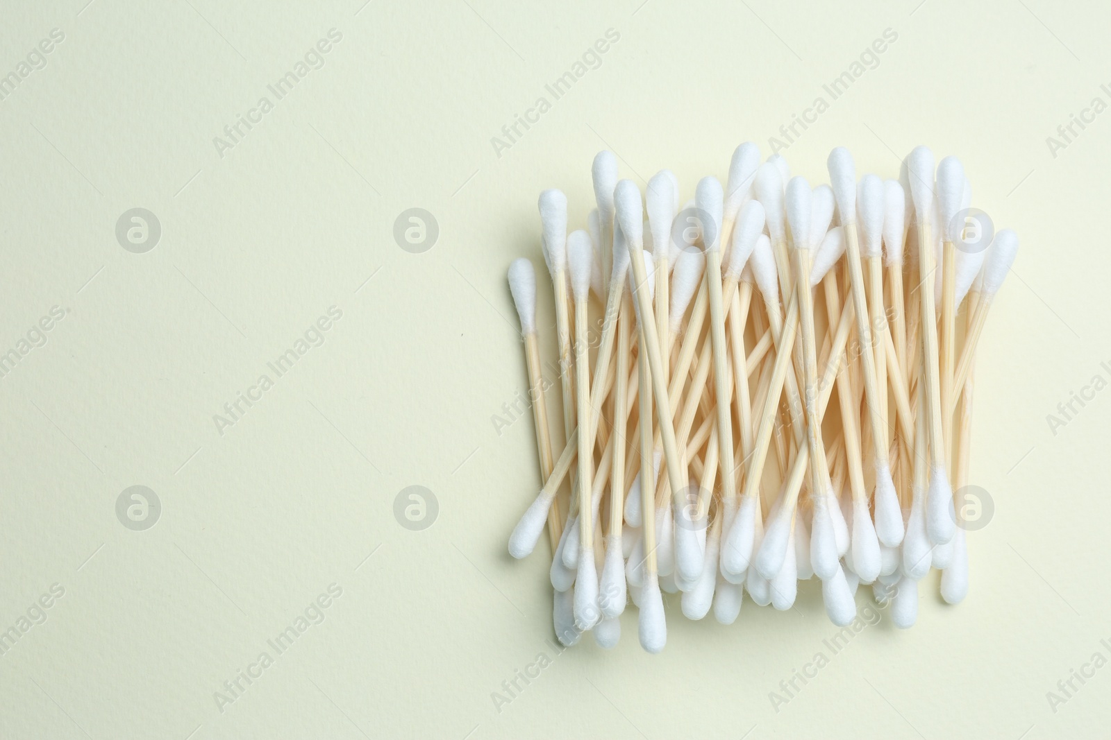 Photo of Heap of cotton buds on beige background, top view. Space for text