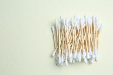 Heap of cotton buds on beige background, top view. Space for text