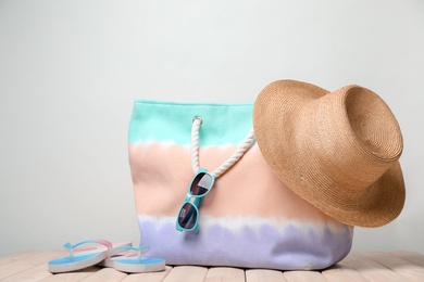 Bag with beach objects on table against light background