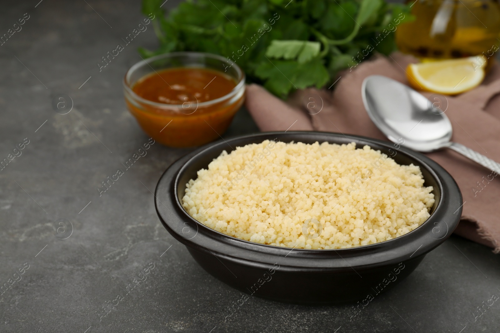 Photo of Bowl of tasty couscous on grey table, space for text