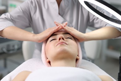 Photo of Cosmetologist making face massage to client in clinic, closeup