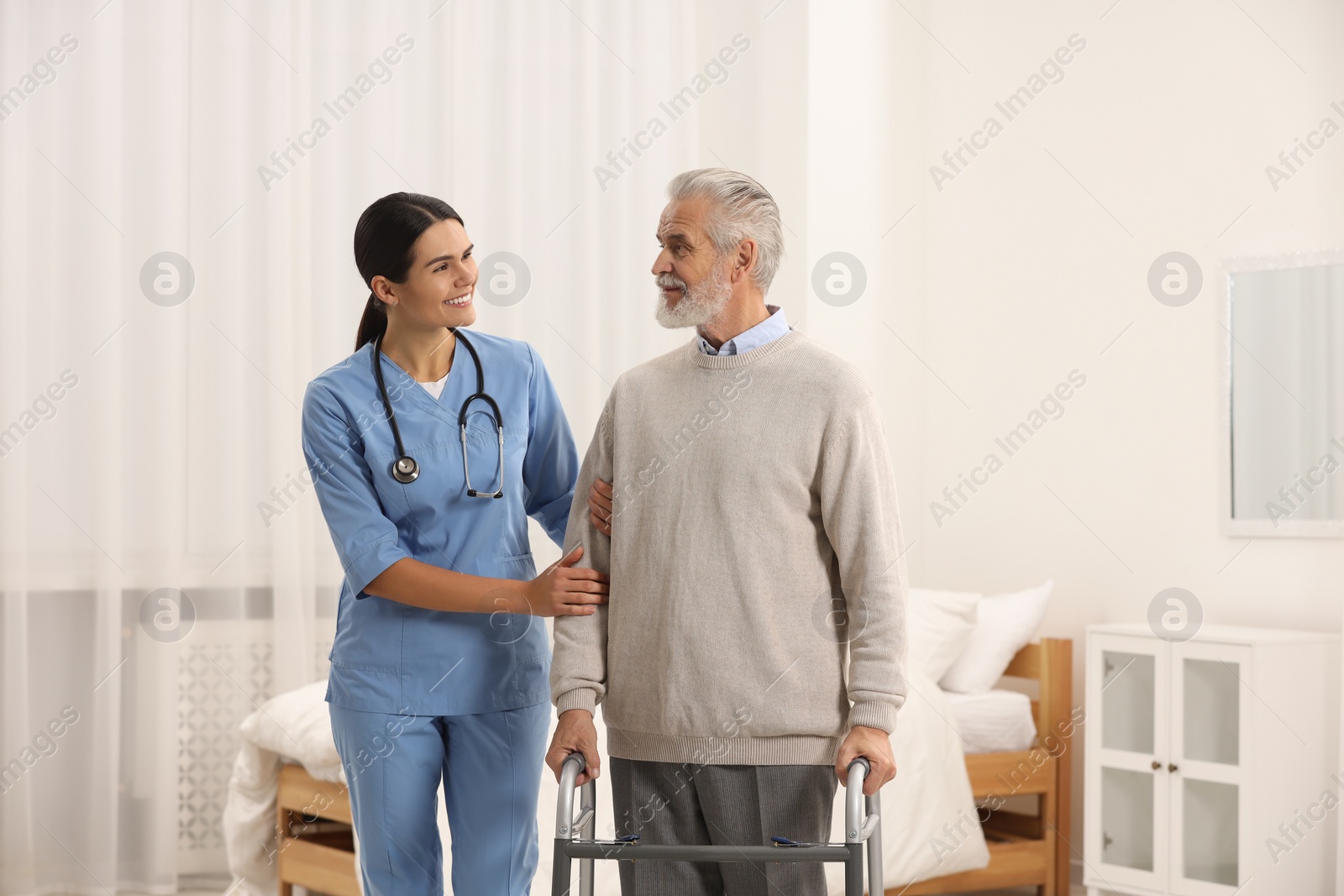 Photo of Health care and support. Smiling nurse with elderly patient in hospital