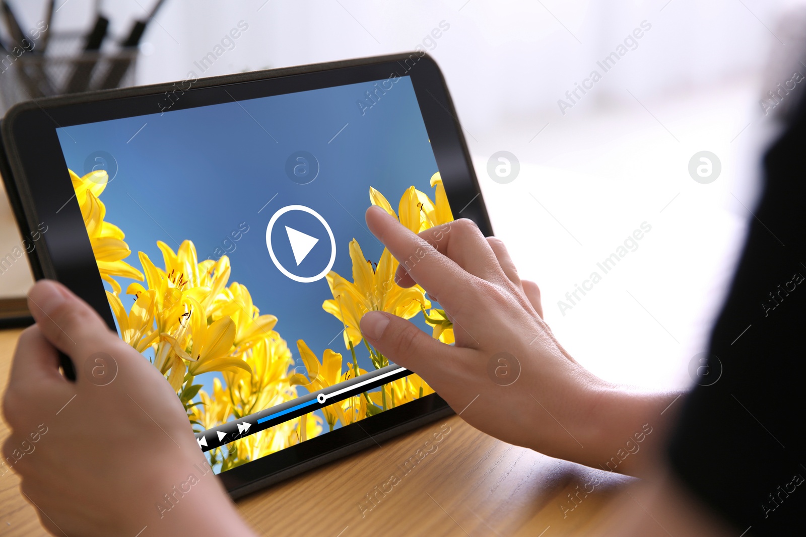 Image of Woman watching video on tablet at wooden desk, closeup