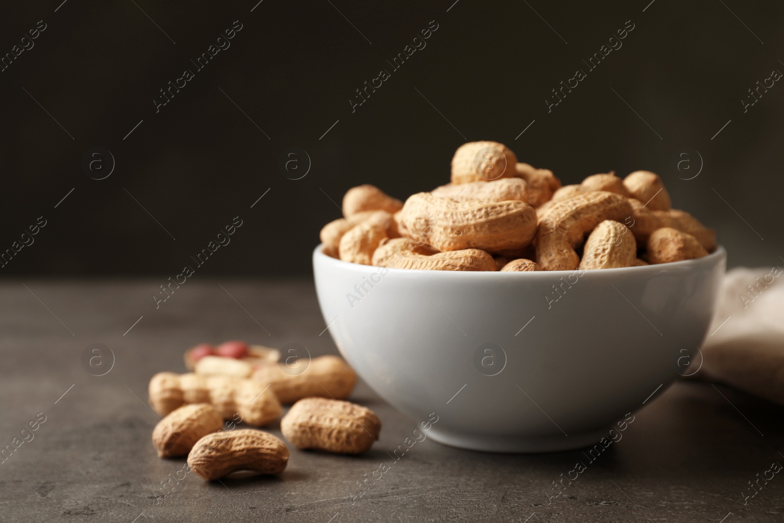 Photo of Bowl with peanuts in shell on table
