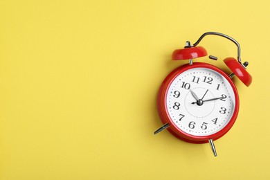 Photo of Alarm clock on yellow background, top view with space for text. School time