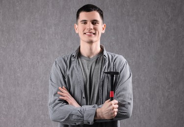 Photo of Young man holding hammer on grey background