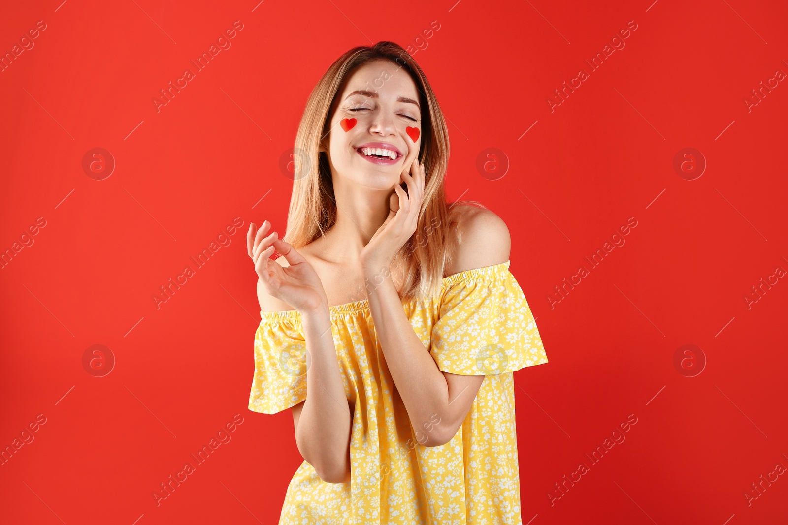 Photo of Portrait of woman with heart shaped stickers on face against color background