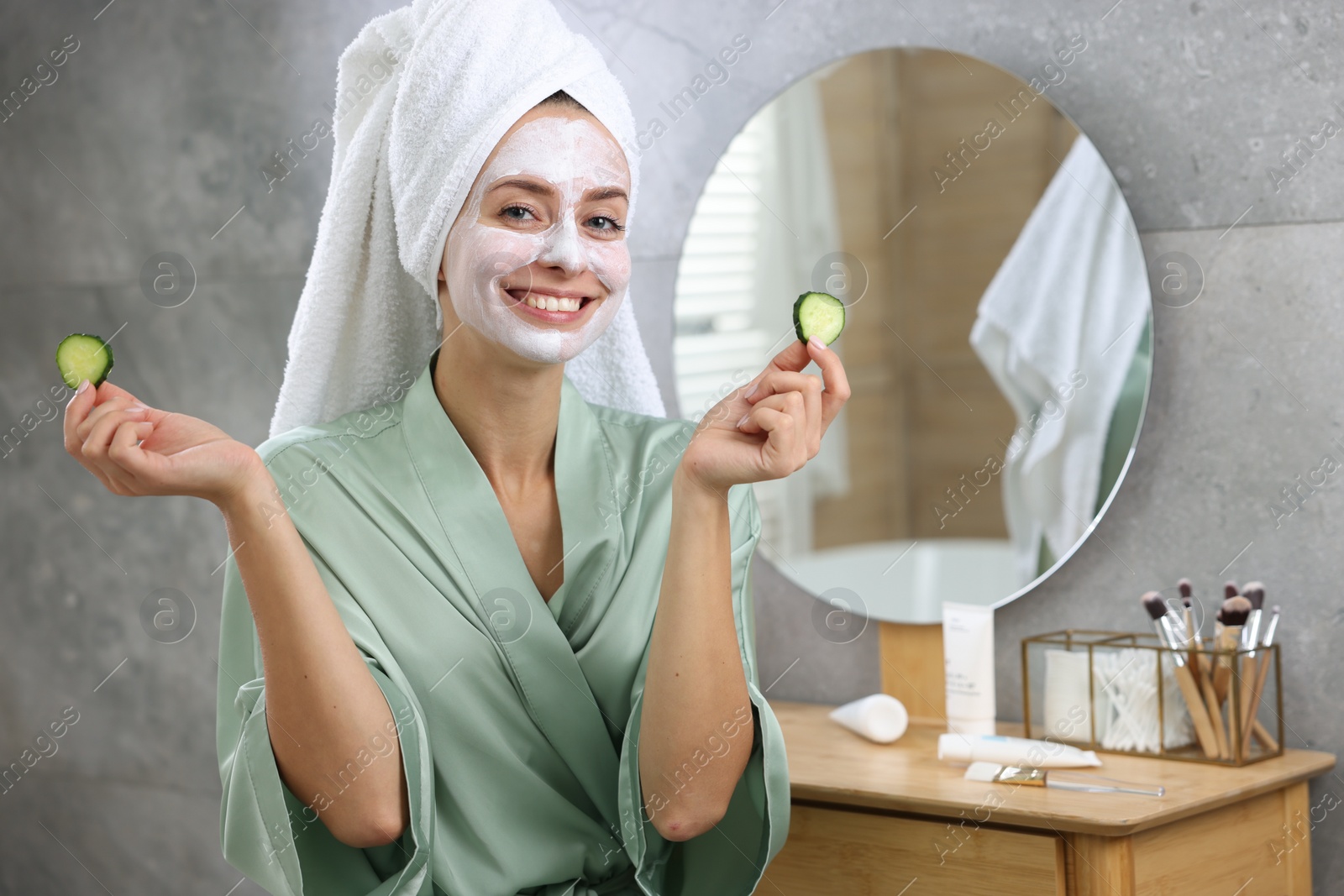 Photo of Woman with face mask and cucumber slices in bathroom, space for text. Spa treatments