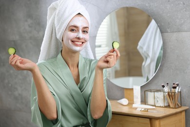 Photo of Woman with face mask and cucumber slices in bathroom, space for text. Spa treatments