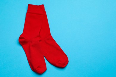 Photo of Red socks on light blue background, flat lay. Space for text