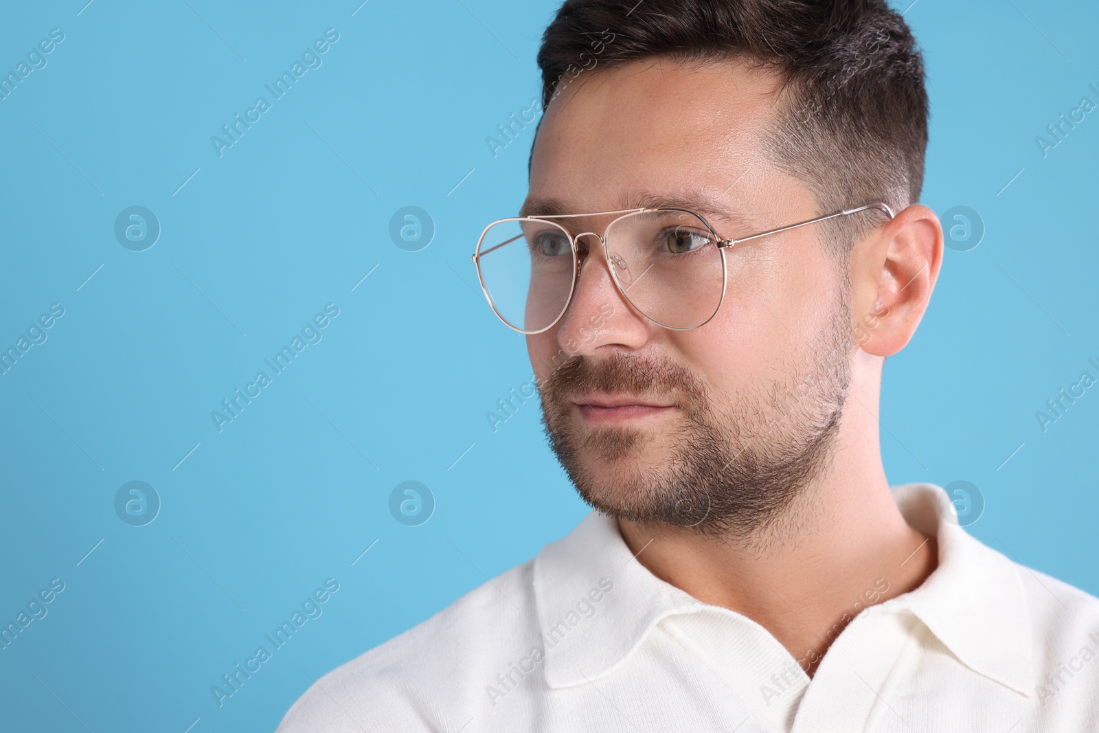 Photo of Portrait of man in stylish glasses on light blue background. Space for text