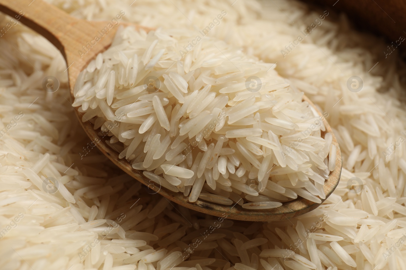 Photo of Raw basmati rice and wooden spoon, closeup