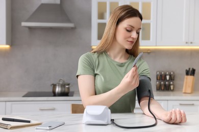 Photo of Woman measuring blood pressure in kitchen, space for text
