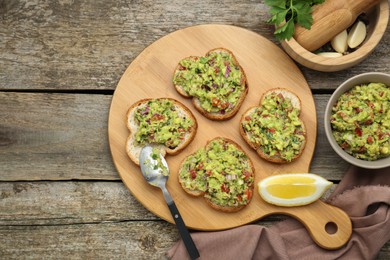 Photo of Slices of bread with tasty guacamole on wooden table, flat lay. Space for text