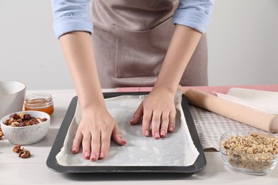 Woman making delicious baklava at white wooden table, closeup