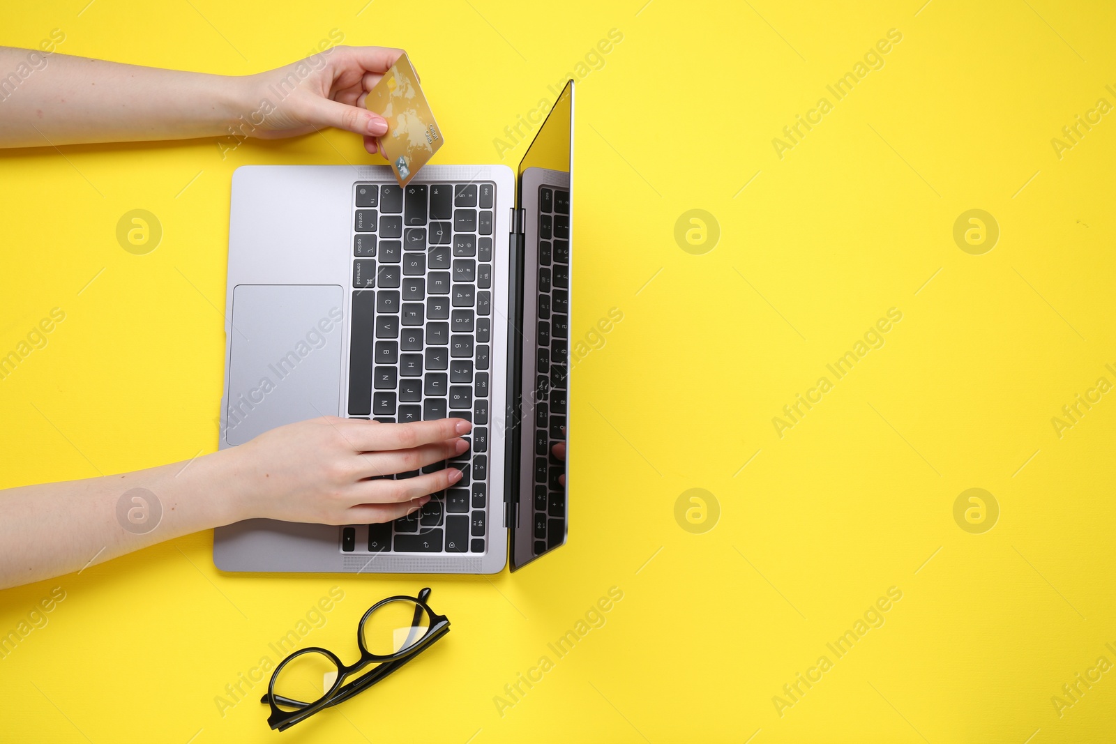 Photo of Online payment. Woman with laptop, credit card and glasses on yellow background, top view. Space for text