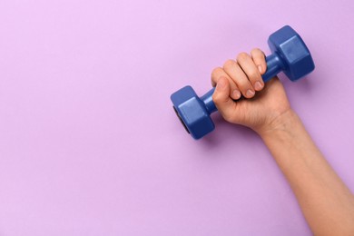 Photo of Woman holding blue dumbbell on violet background, top view. Space for text