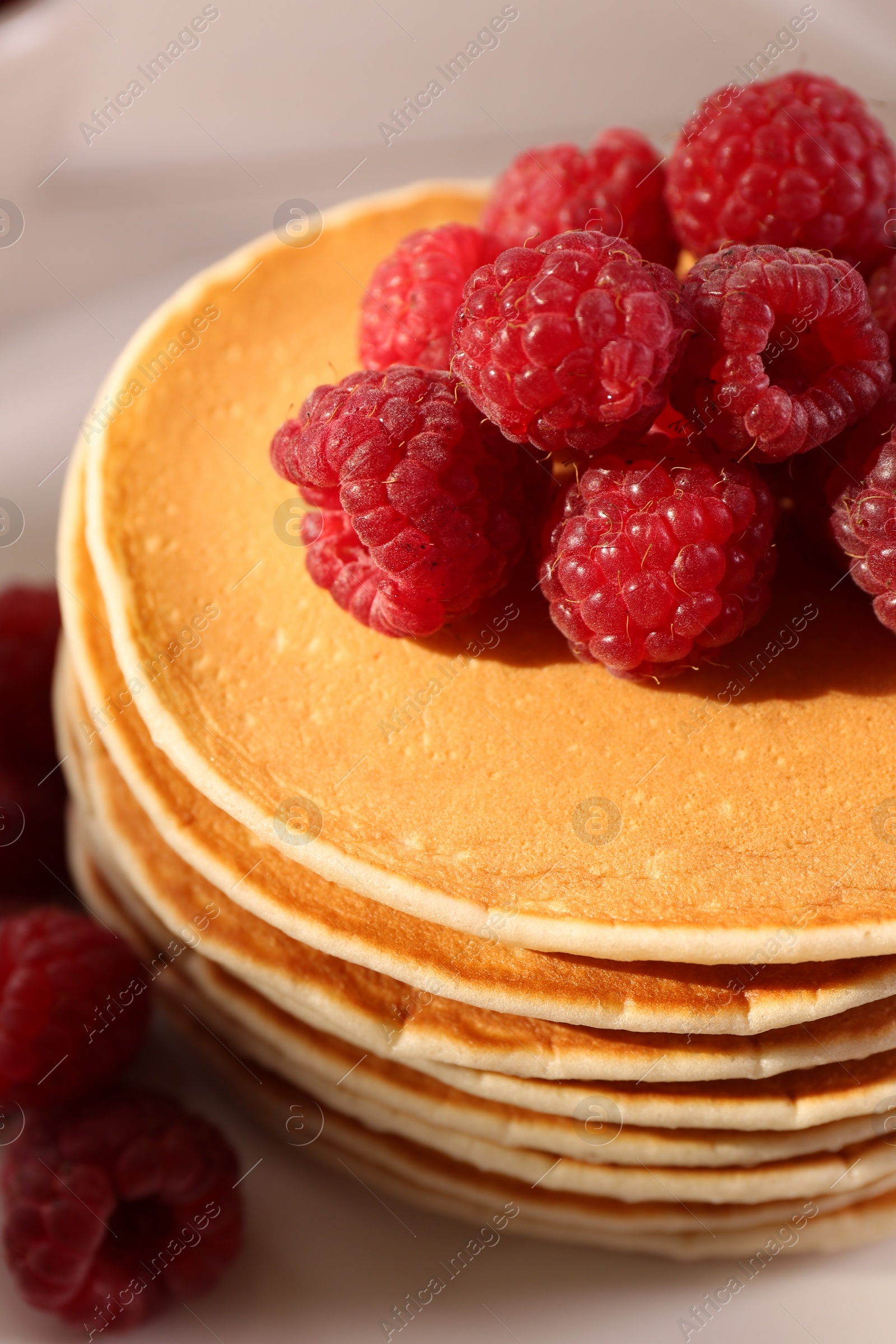 Photo of Stack of tasty pancakes with raspberries on plate, closeup