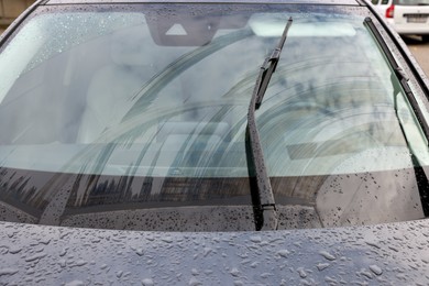 Photo of Car wipers cleaning water drops from windshield glass, closeup