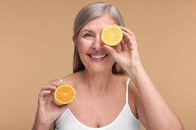 Photo of Beautiful woman with halves of orange rich in vitamin C on beige background