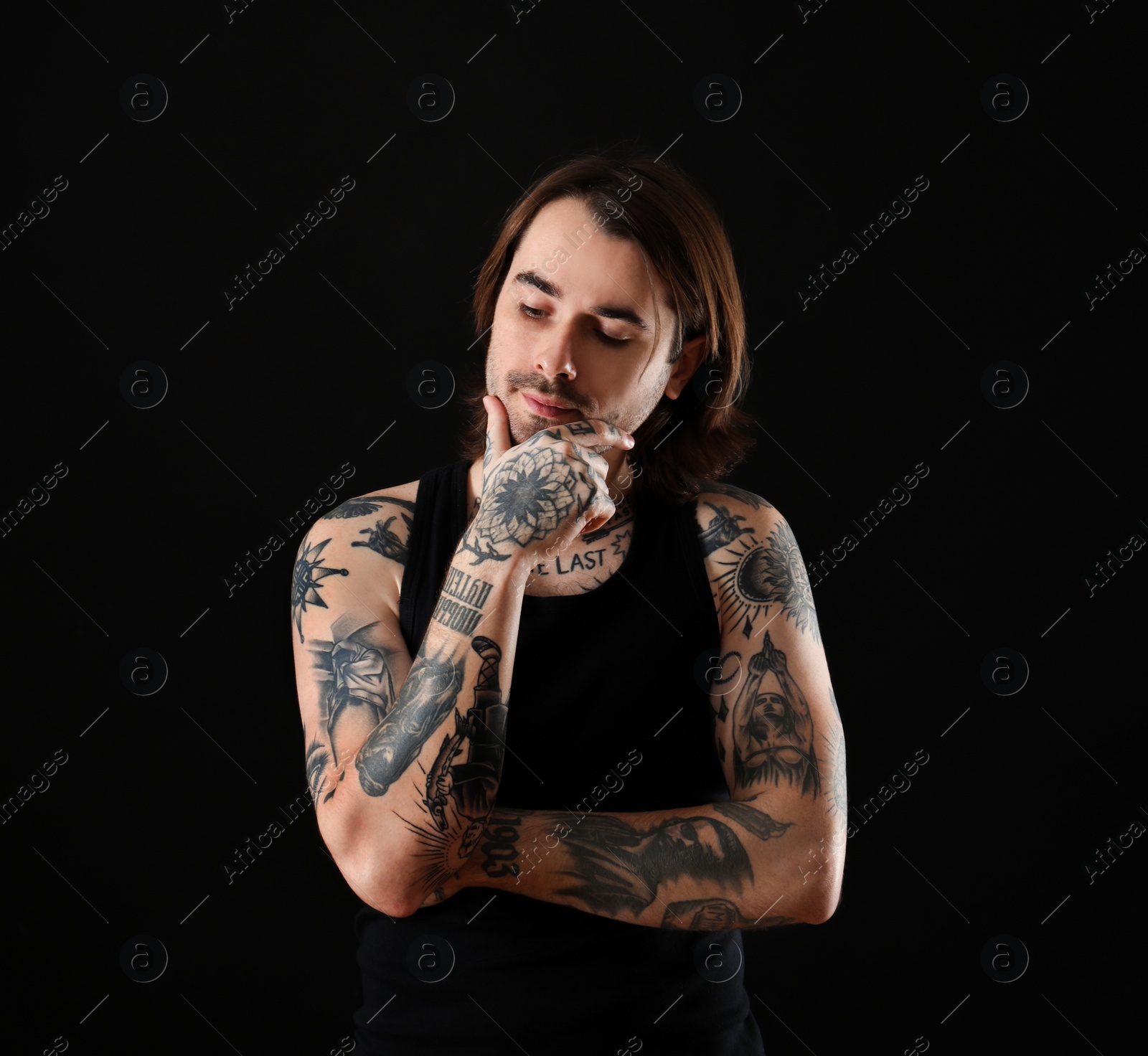 Photo of Young man with tattoos on body against black background