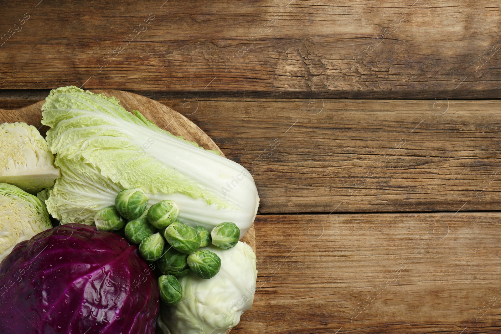 Photo of Different types of cabbage on wooden table, top view. Space for text