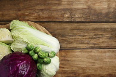 Different types of cabbage on wooden table, top view. Space for text