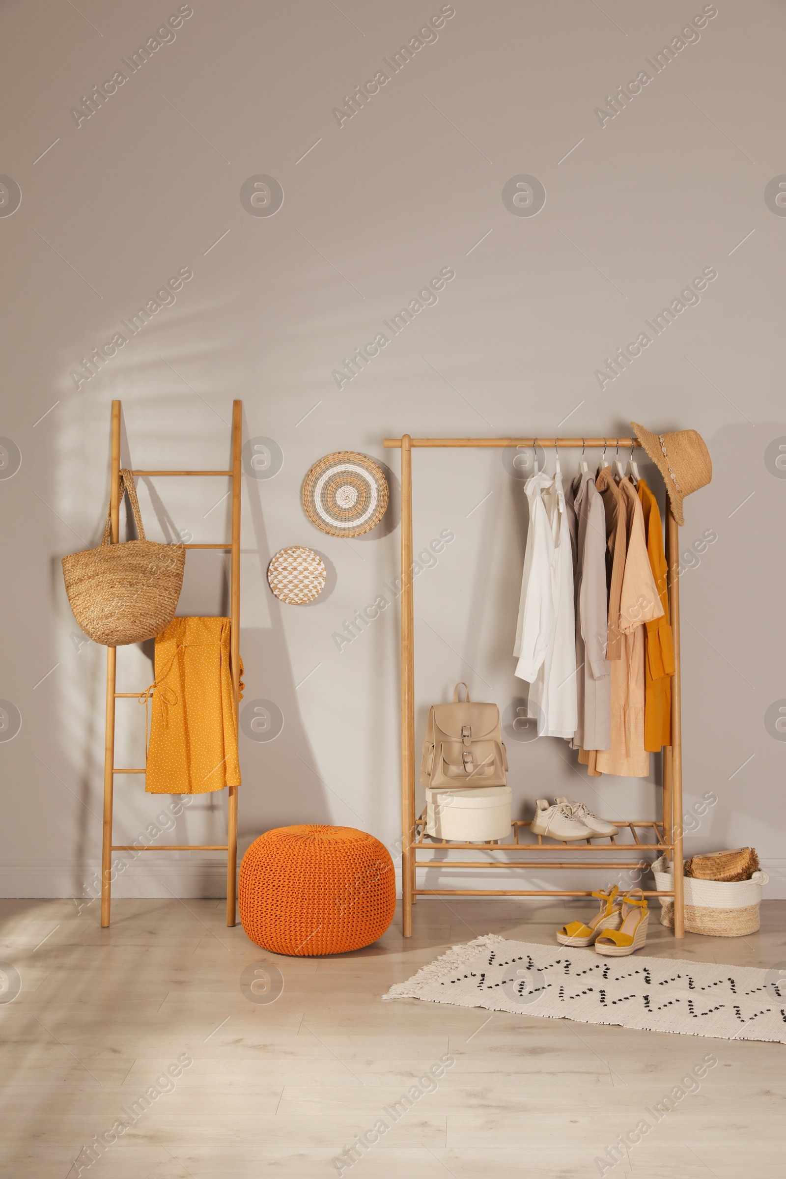 Photo of Modern dressing room interior with stylish clothes, shoes and orange pouf