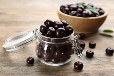 Photo of Tasty acai berries in glass jar on wooden table, closeup