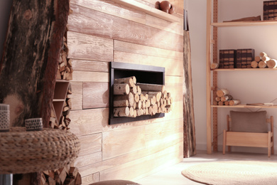 Photo of Decorative fireplace with stacked wood in cozy living room interior