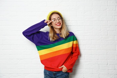 Photo of Beautiful young woman in warm sweater with hat near white brick wall