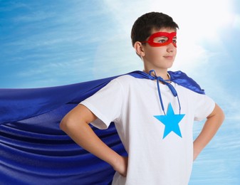 Image of Boy in superhero costume against blue sky