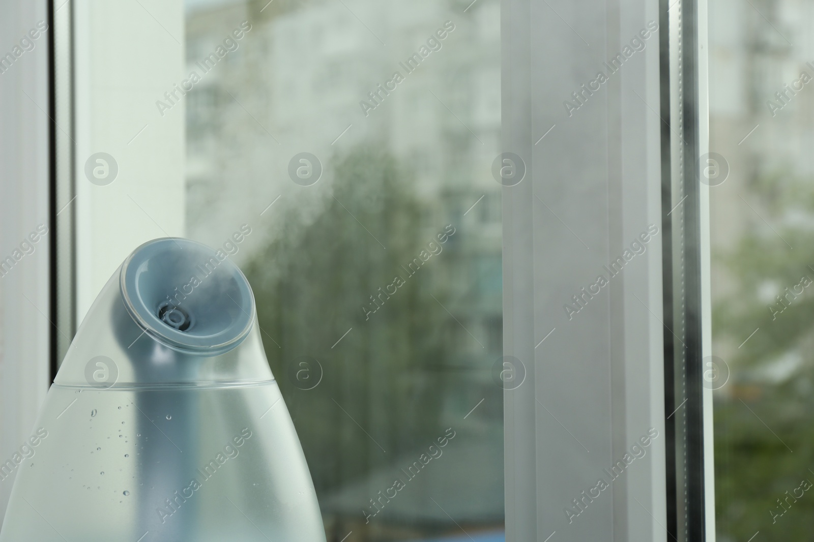 Photo of Modern air humidifier near window indoors, closeup. Space for text