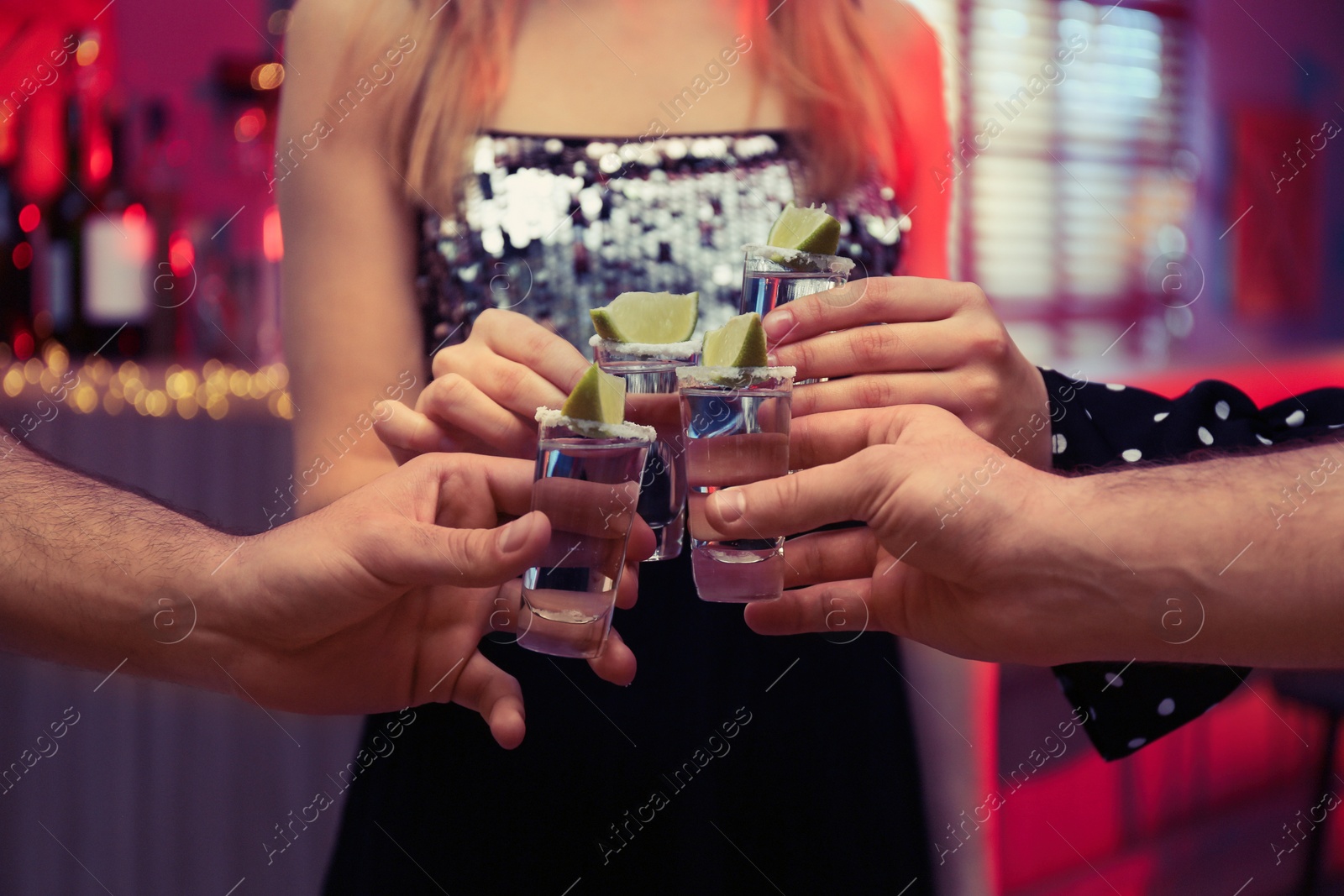 Photo of Young people toasting with Mexican Tequila shots in bar, closeup