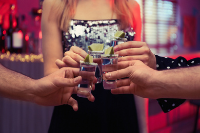 Young people toasting with Mexican Tequila shots in bar, closeup