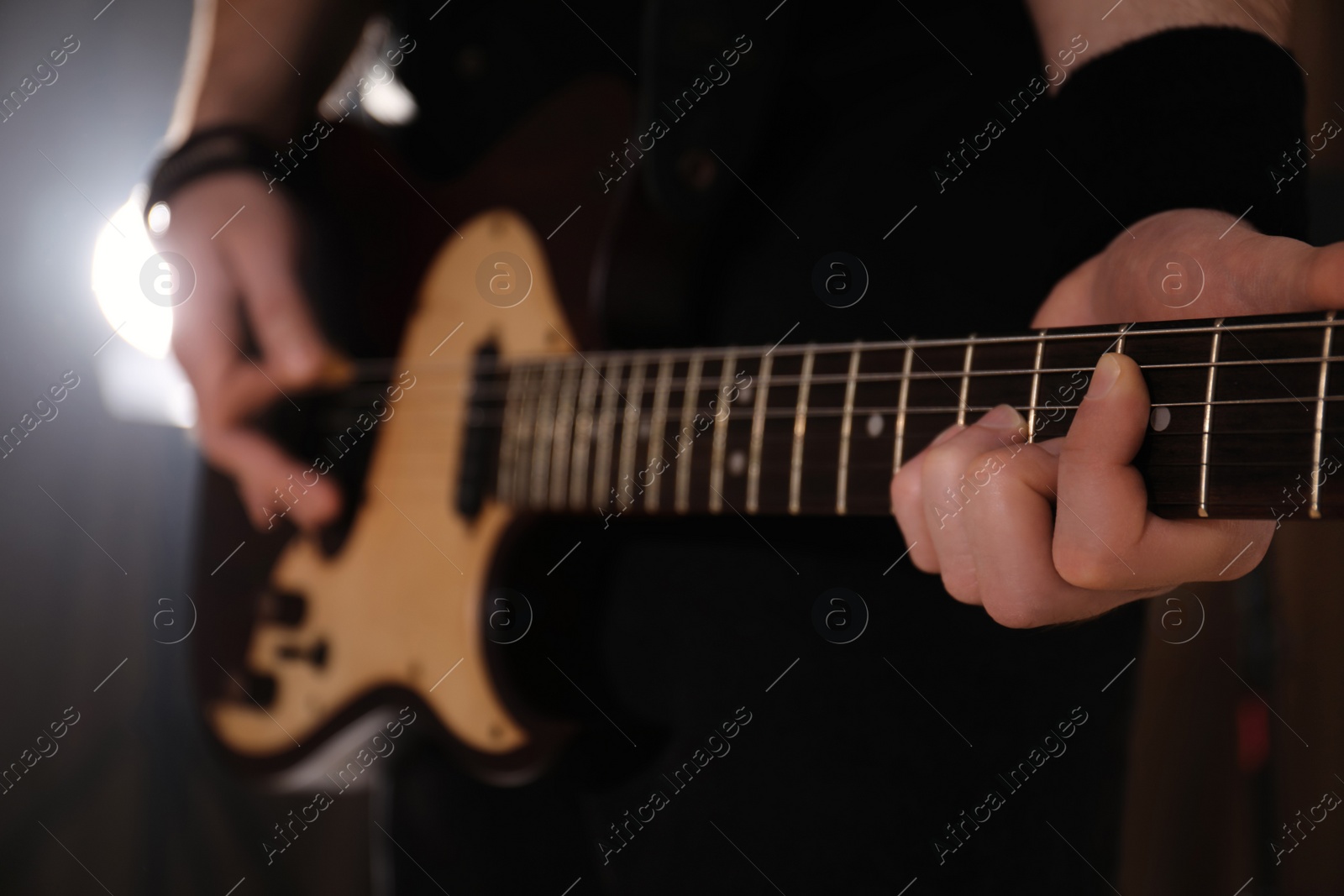 Photo of Man playing electric guitar on stage, closeup. Rock music