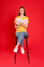 Photo of Young woman reading book on color background