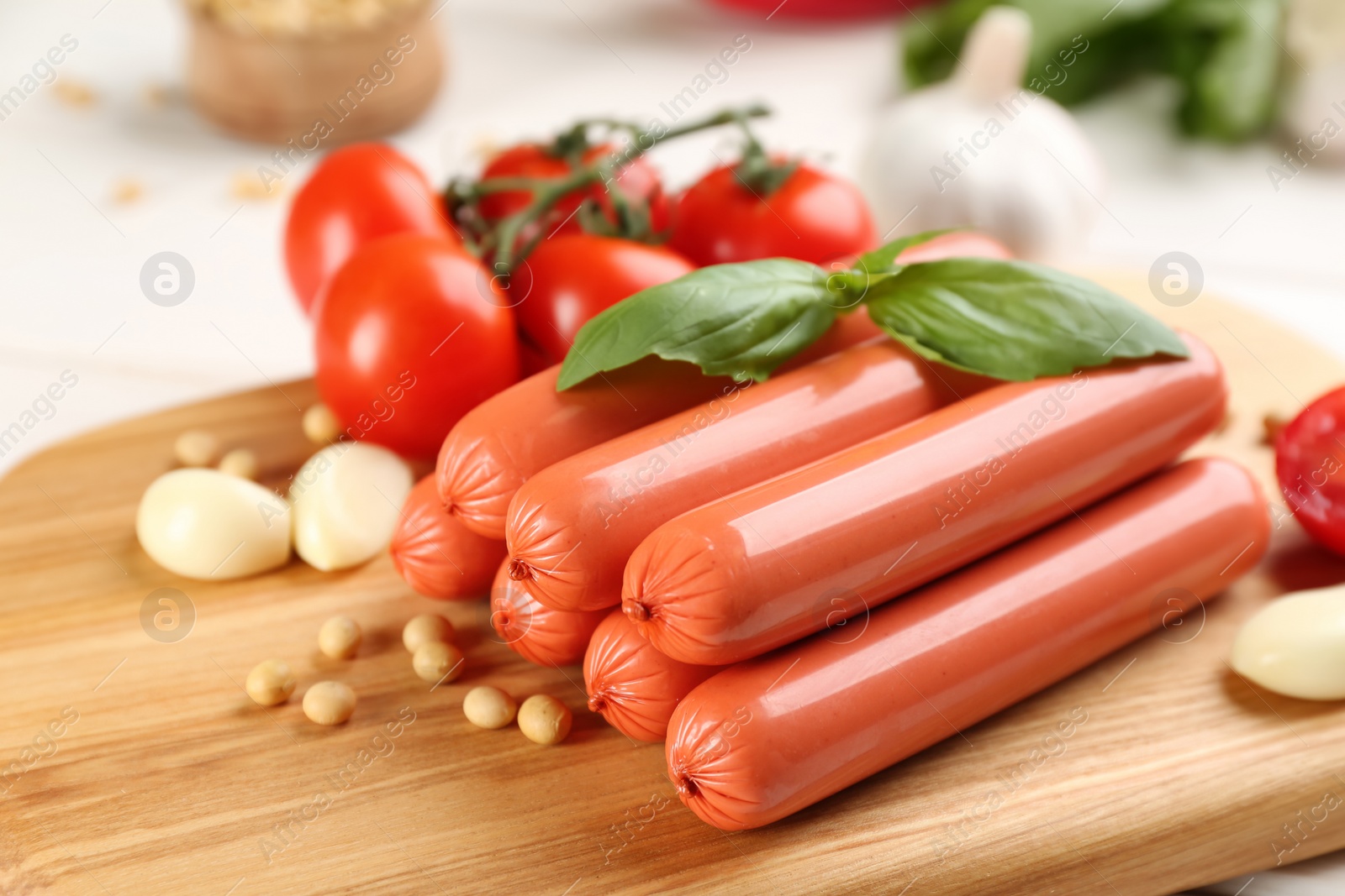 Photo of Fresh raw vegetarian sausages and vegetables on wooden board, closeup