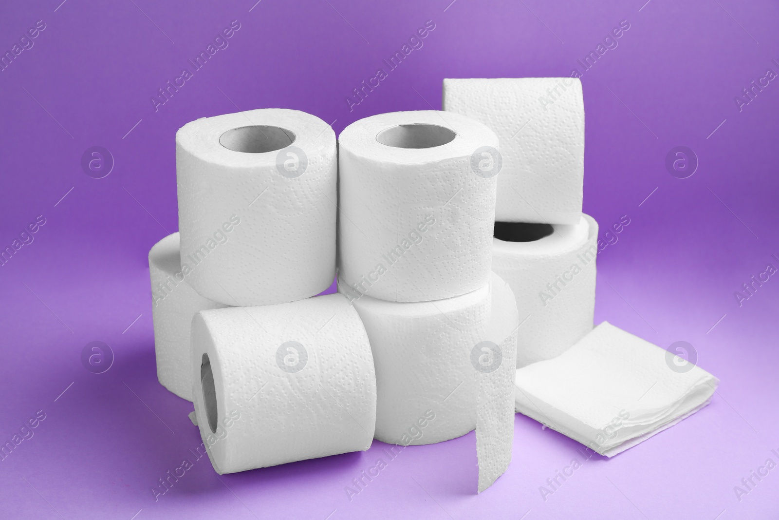 Photo of Soft toilet paper rolls on violet background