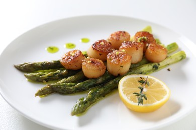 Delicious fried scallops with asparagus, lemon and thyme on white background, closeup