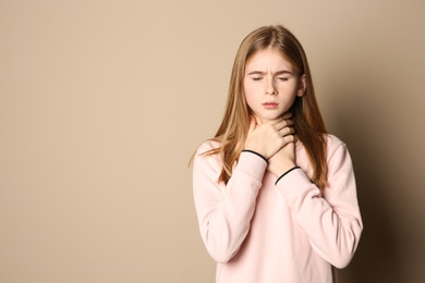 Photo of Teenage girl suffering from cough on color background. Space for text