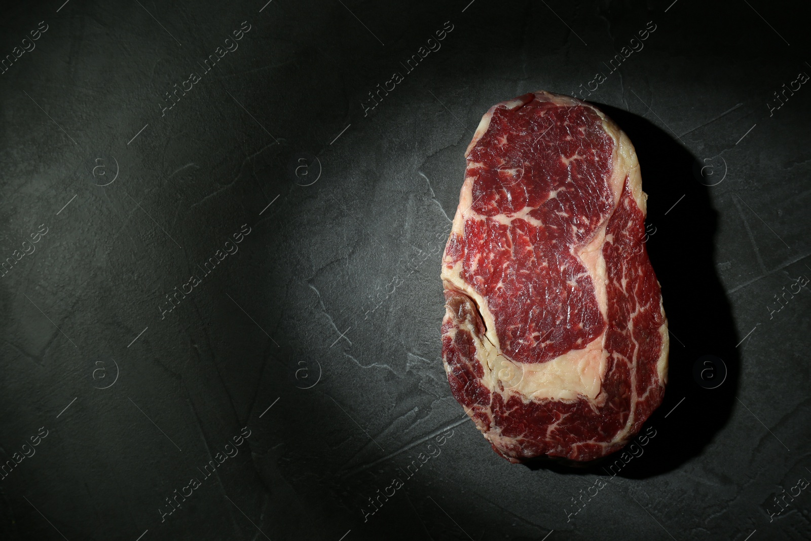 Photo of Piece of raw beef meat on grey table, top view. Space for text