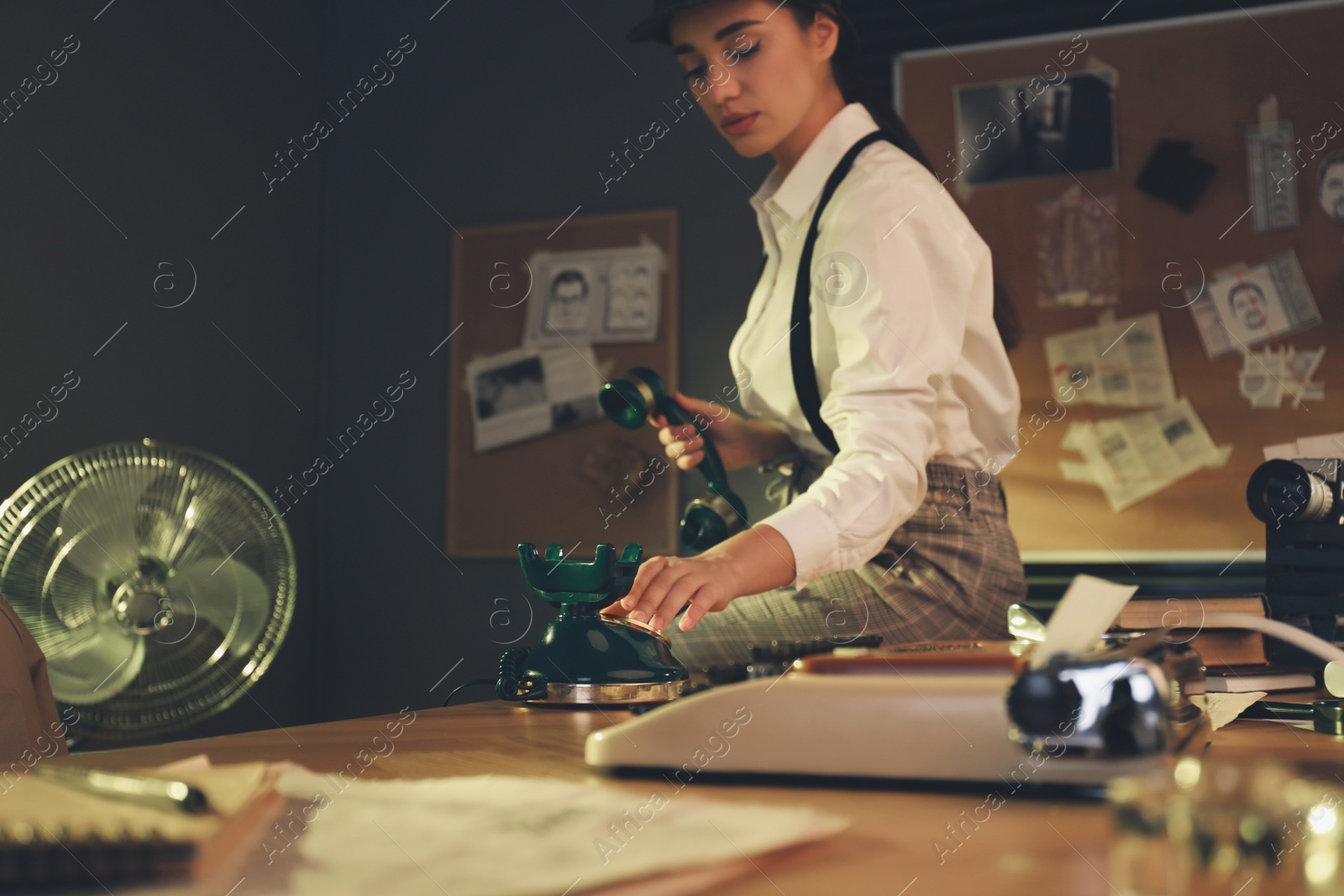 Photo of Old fashioned detective dialing telephone number in office