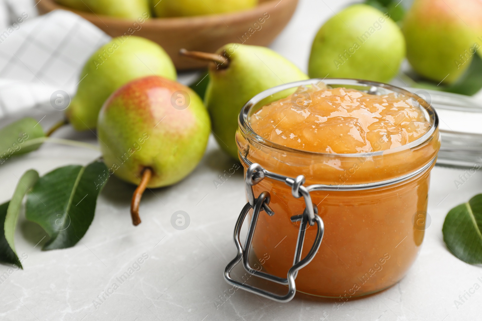 Photo of Delicious pear jam and fresh fruits on light grey table. Space for text