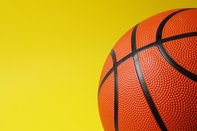 Photo of Basketball ball on yellow background, closeup. Space for text