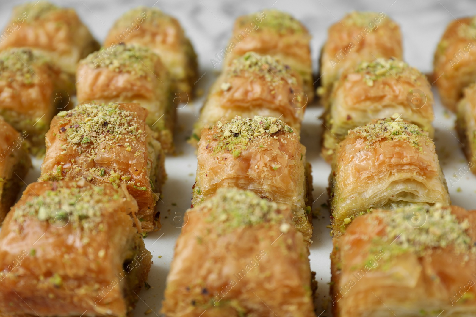 Photo of Delicious fresh baklava with chopped nuts on white table, closeup. Eastern sweets