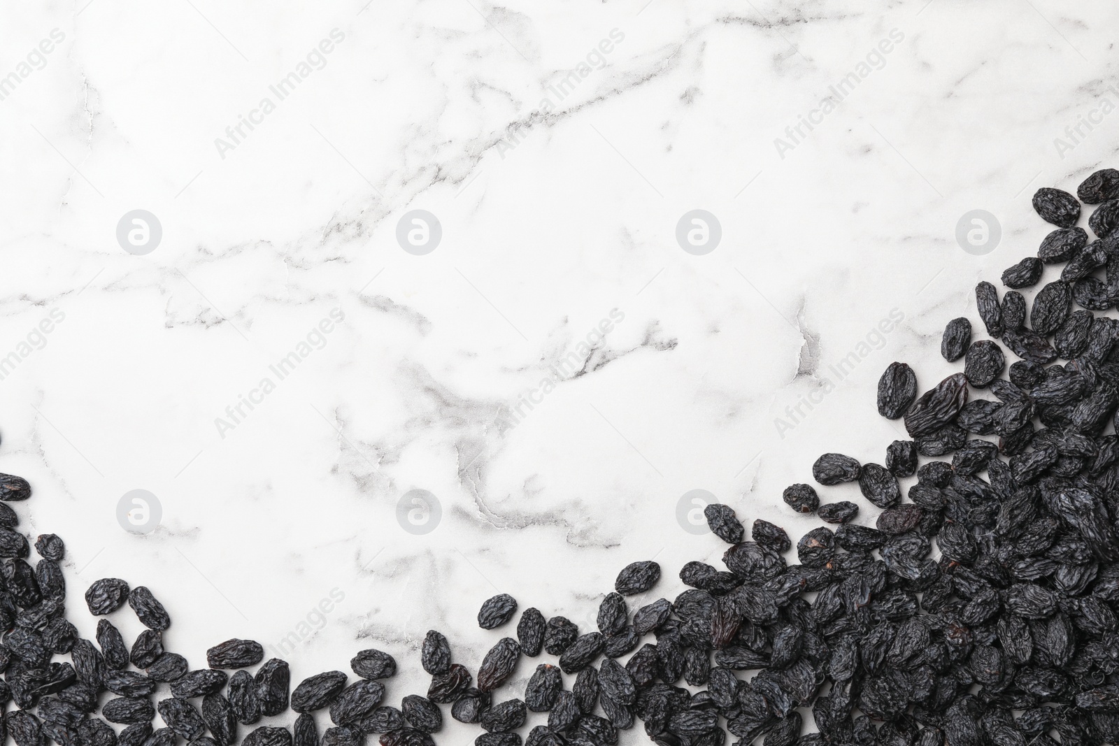 Photo of Many raisins and space for text on marble background, top view. Dried fruit as healthy snack