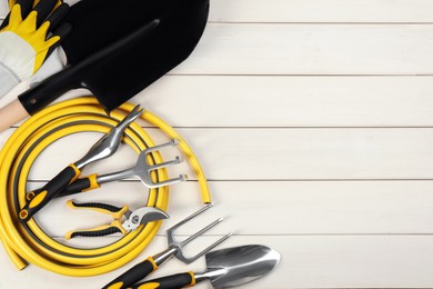 Flat lay composition with gardening tools on white wooden background. Space for text